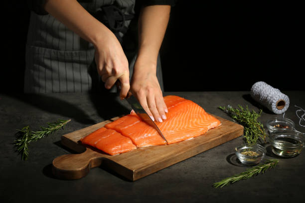 donna che taglia il filetto di salmone fresco a tavola - ready to cut foto e immagini stock