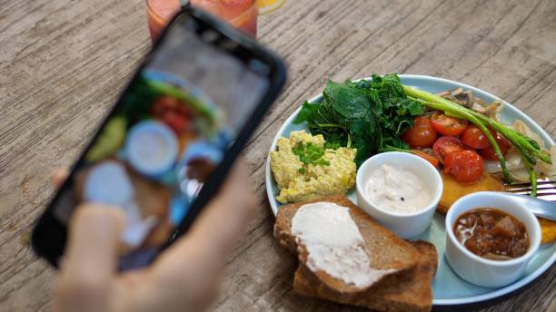 Hand of a healthy lifestyle blogger takes a picture of plant based lunch of a tofu scramble, toasts and veggies served on a wooden table Hand of a healthy lifestyle blogger takes a picture of plant based lunch of a tofu scramble, toasts and veggies served on a wooden table image based social media photos stock pictures, royalty-free photos & images