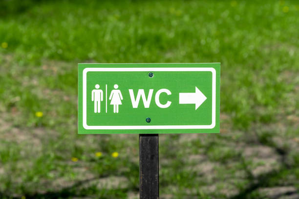 logo wc, signe de toilettes publiques dans la rue sur fond d’herbe. - public restroom bathroom restroom sign sign photos et images de collection