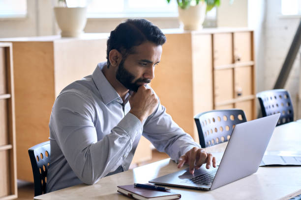 istock Concentrated Indian ceo businessman working in modern office using laptop. 1350800602