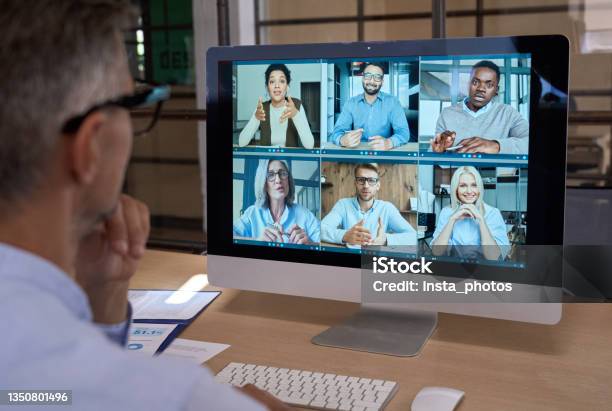Businessman Talking With Team Leading Virtual Meeting On Computer Over Shoulder Stock Photo - Download Image Now