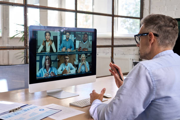 Corporate manager leading videoconference with team business people on computer. Corporate leader manager leading videoconference with diverse team business people having digital group video call conference working in office at online virtual meeting on pc computer. Over shoulder remote location stock pictures, royalty-free photos & images