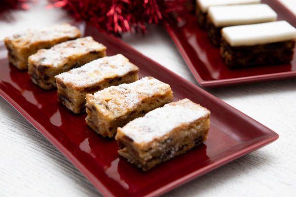 istock Stollen slices and mini Christmas cake slices in a row on rectangular red serving plates, with tinsel 1350805932