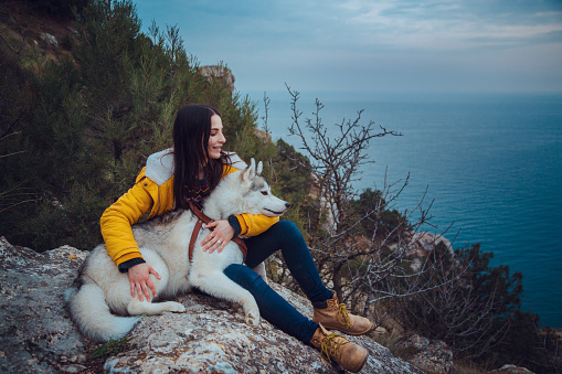 beautiful young woman enjoying a walk with her pet siberian husky, spring nature, adventure and discovery concept