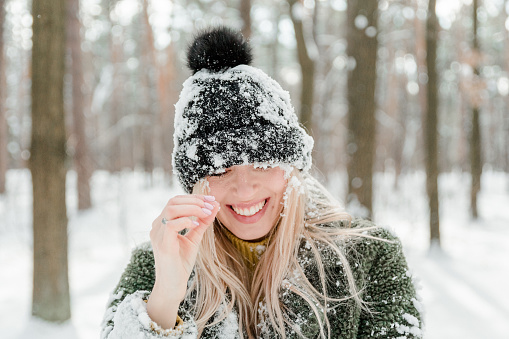 Pretty young blond woman, dressed warmly, with a scarf and mittens. Beautiful girl having fun in the snow
