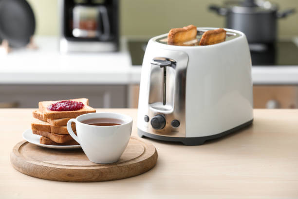 tostadora con rebanadas de pan y taza de café en la mesa - tostadora fotografías e imágenes de stock