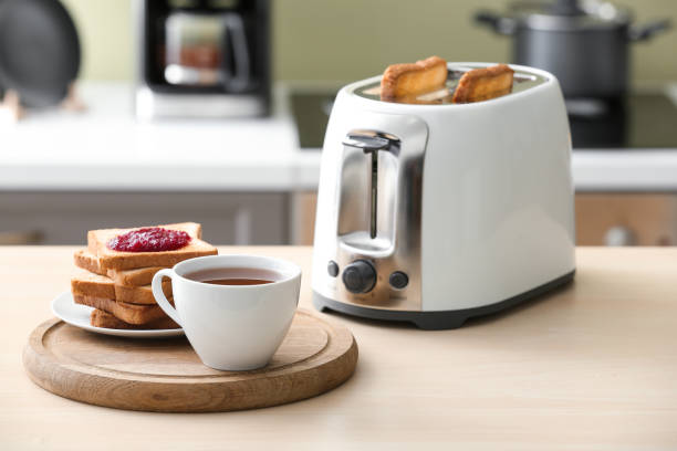 Toaster with bread slices and cup of coffee on table stock photo