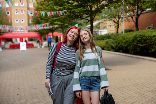 Sisters standing together looking at the camera after arriving at a university campus. One of them is starting her new journey, moving into a halls of residence in London.