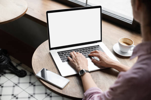 istock Woman using laptop computer at cafe with white blank empty screen mock-up 1350815300