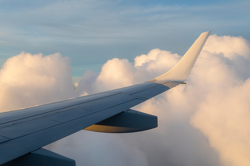 Close-up of airplane wing flying above a cloudy sky.