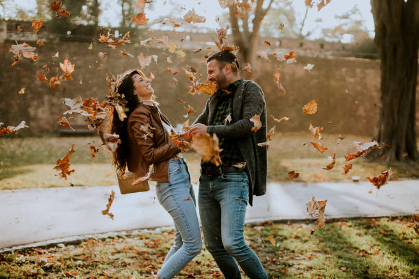 istock Young couple having fun with leaves in autumn park 1350815862