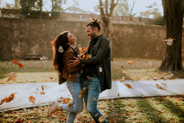 istock Young couple having fun with leaves in autumn park 1350815890