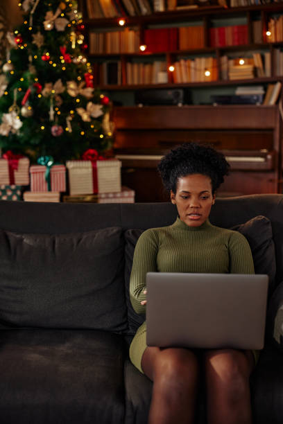 istock African american woman sitting on sofa and using laptop 1350817670