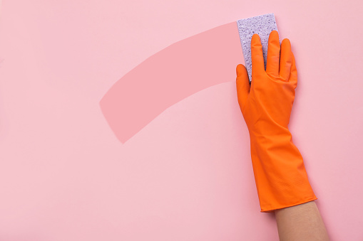 Woman holding sponge on color background. Cleaning service