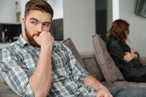 istock Young sad quarrel loving couple sitting on sofa indoors. 1350822511