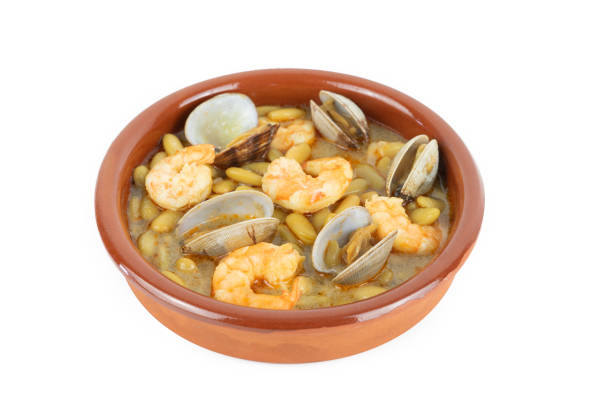 Fabas verdinas with prawns and clams in an earthenware casserole on a white background. Copy space. Green beans with prawns and clams in an earthenware casserole on a white background. Copy space. fabes stock pictures, royalty-free photos & images