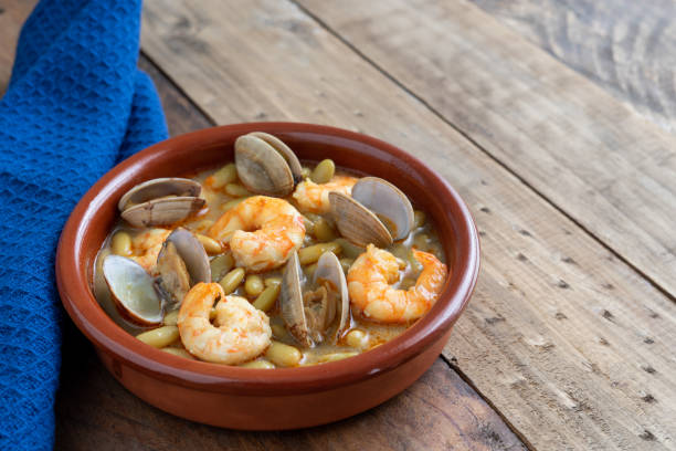 Green beans with prawns and clams in earthenware casserole on wood background. Copy space. top view. Fabas verdinas with prawns and clams in an earthenware casserole on a wooden base. Copy space. super view fabes stock pictures, royalty-free photos & images