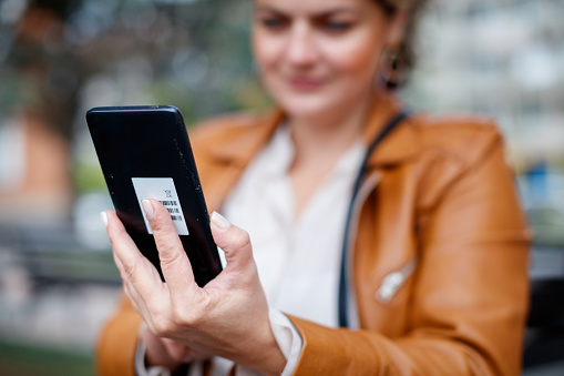 Mid adult woman using smart phone for video call, focus on hand