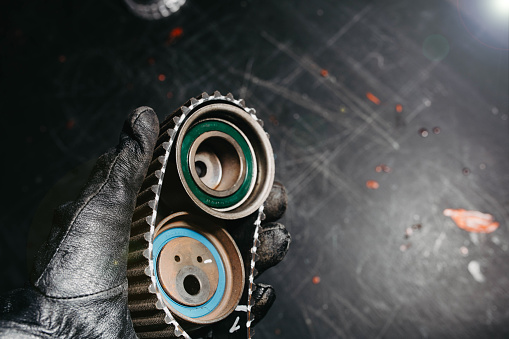 automotive timing belt on a black background. Replacement concept for idler pulleys and engine belts.