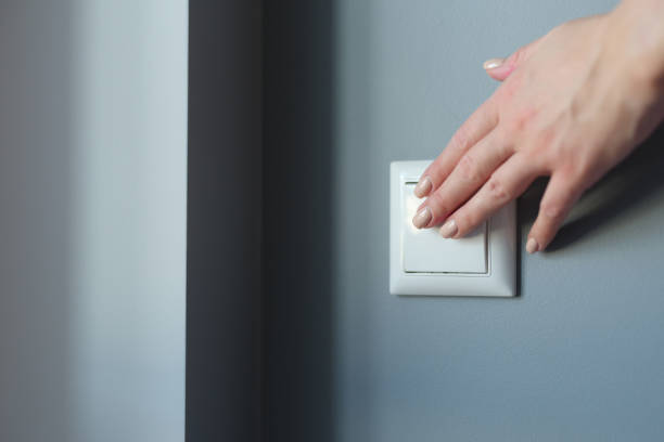 istock Female hand pressing light switch in apartment closeup 1350824684