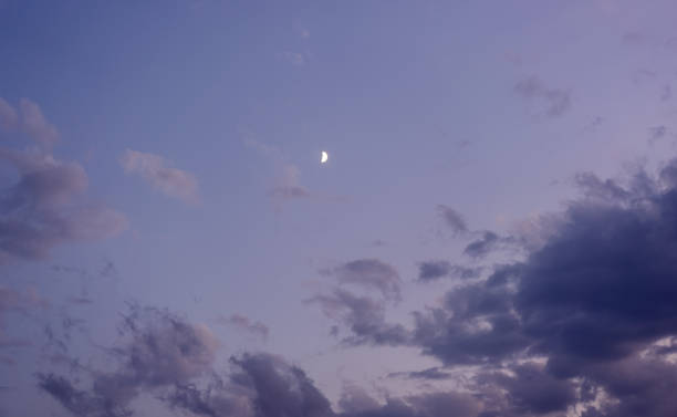 istock Half moon is seen in daytime, in blue sky with wispy clouds 1350826667