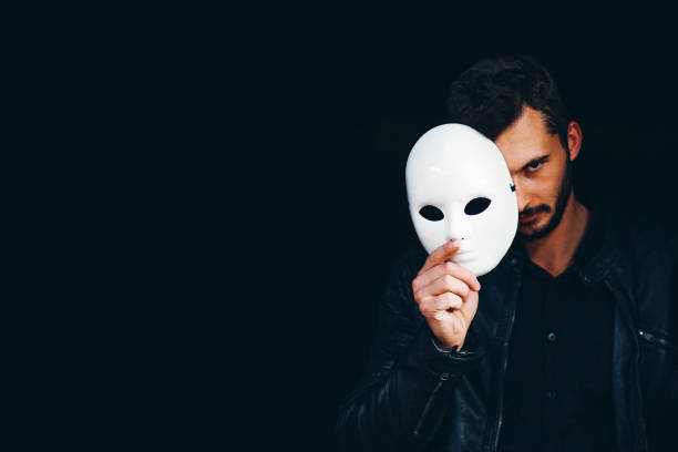 istock Handsome Strong Man Hides Behind a Mask in the Dark Background 1350827350