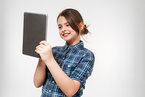 Image of happy young girl using tablet computer isolated over white background.