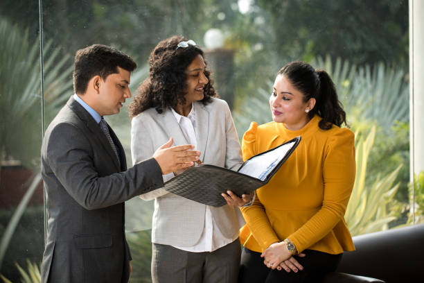 business colleagues discussing over filed reports at office - indiana imagens e fotografias de stock