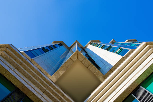 Low angle view on office building facade in  blue mirror glass and concrete blocks, diminishing perspective towards clear sky