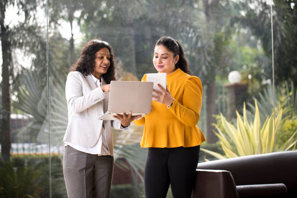 Two businesswomen using laptop and digital tablet at office stock photo