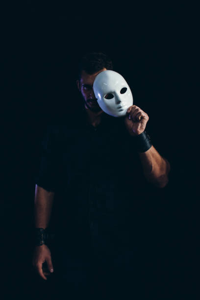 istock Handsome Strong Man Hides Behind a Mask in the Dark Background 1350827912