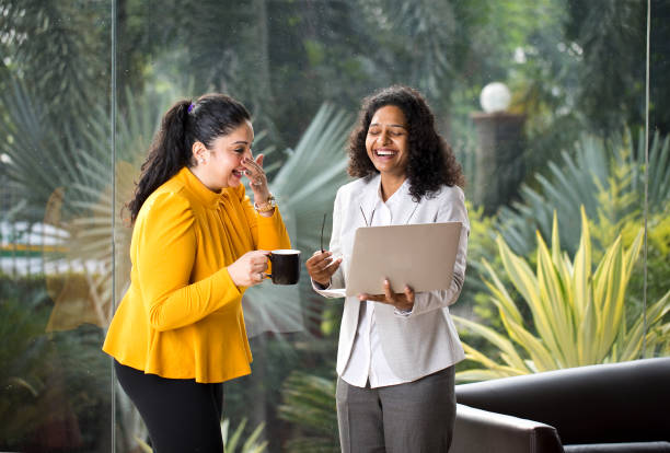 dos mujeres de negocios felices discutiendo en la oficina - coffee buzz fotografías e imágenes de stock