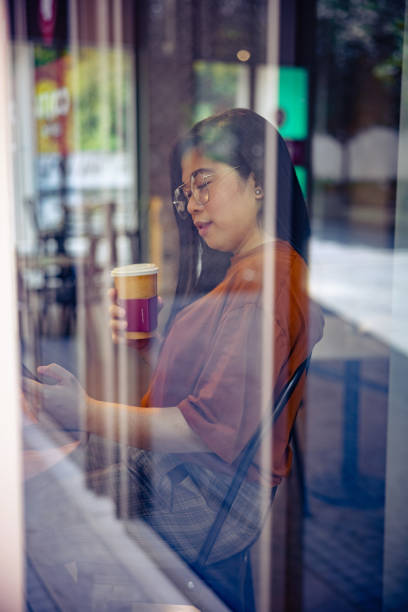 blick durch das café-fenster auf die frau am tisch, mit dem smartphone - 4797 stock-fotos und bilder