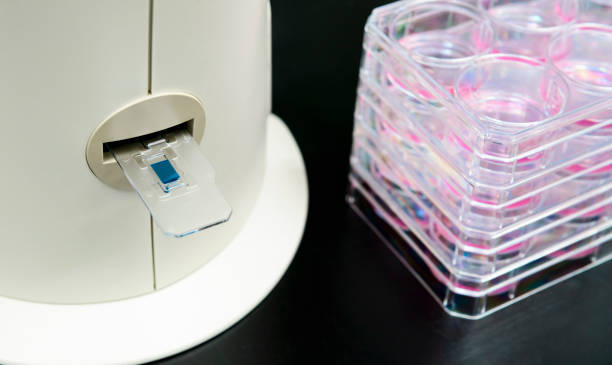 istock Inserting slide containing trypan blue-stained human cells into automated cell counter 1350829049