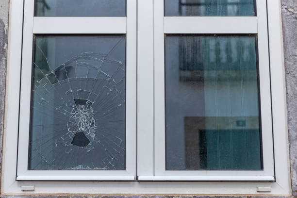 Cracked glass in a plastic vacuum window frame. A damaged window due to vandalism, natural disaster, or accident. stock photo