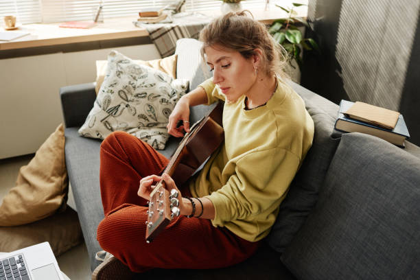 istock Woman playing guitar in the room 1350830133
