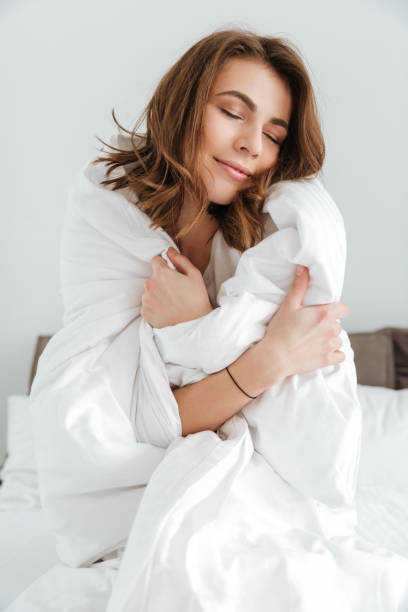 istock Pretty lady dressed in white t-shirt sitting on bed 1350831902