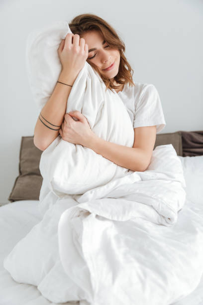 istock Pretty lady dressed in white t-shirt sitting on bed 1350833261