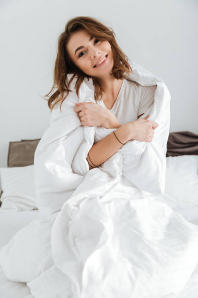 istock Pretty lady dressed in white t-shirt sitting on bed 1350833281