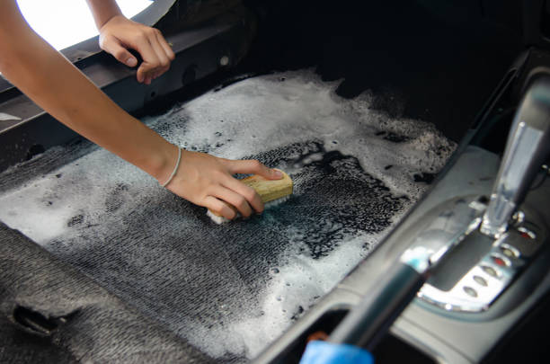 Wash the car carpet.Detailing on interior of modern car.Clean by using a brush and cleaning solution on the car carpet. stock photo
