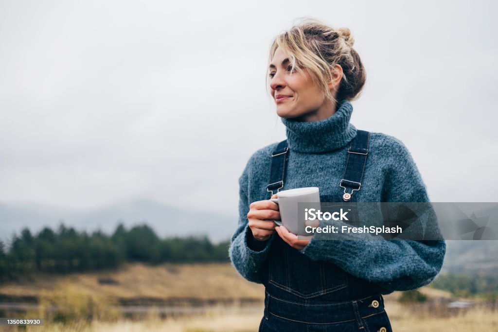 Beautiful Woman Drinking Tea in Nature Young female enjoying her cup of tea outdoors Women Stock Photo