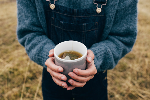 Close up photo of woman hands holding cup of tea outdoors