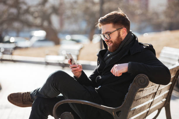 istock Cheerful man sitting and using smartphone in the city 1350834136