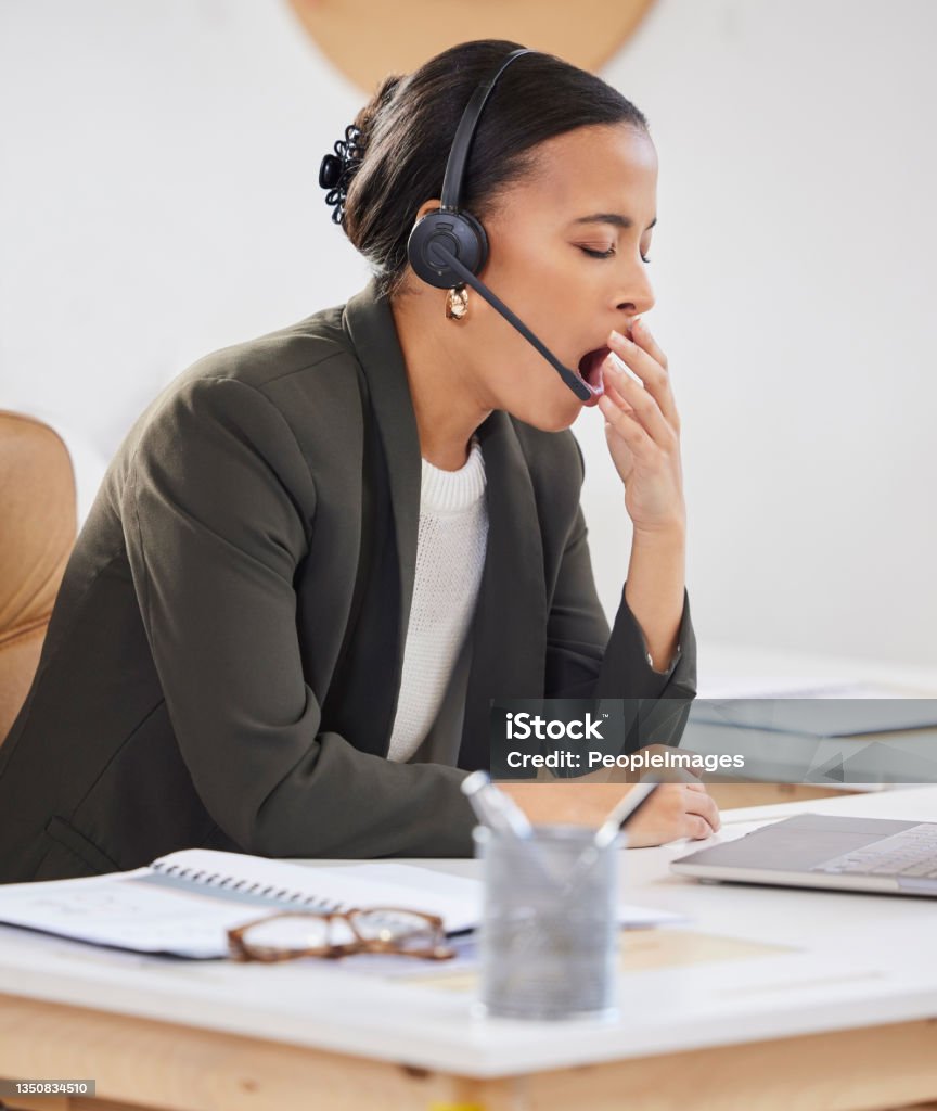 Shot of a young businesswoman yawning while working in a call centre Boredom sets in when work gets slow Boredom Stock Photo