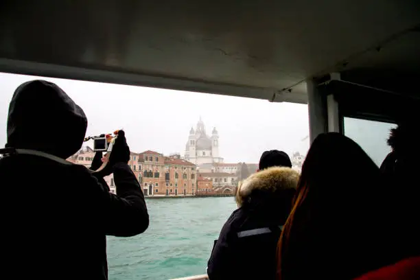 tourists are on the boattrip and taking photo to Venice horizontal photo weather is rainy