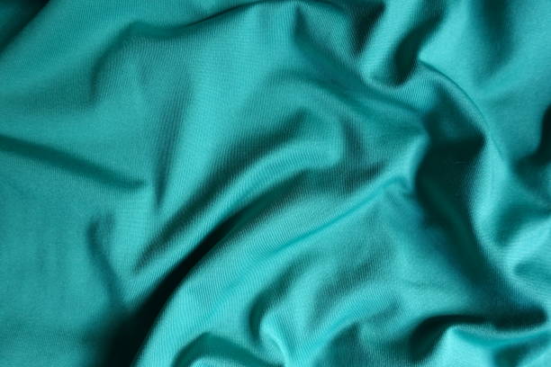 Surface of blue green polyester fabric with soft folds Surface of blue green polyester fabric with soft folds unprinted stock pictures, royalty-free photos & images