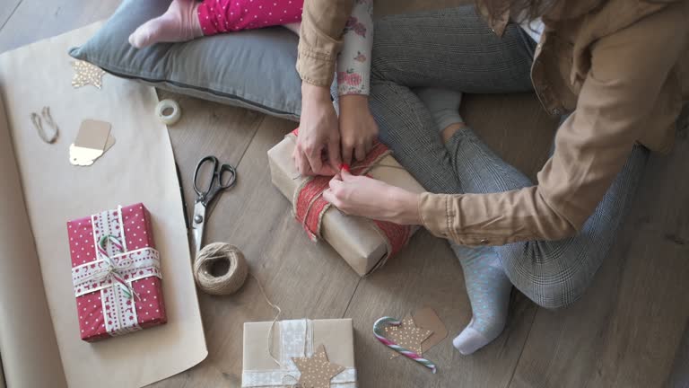 Mother And Daughter Wrapping Christmas Presents At Home