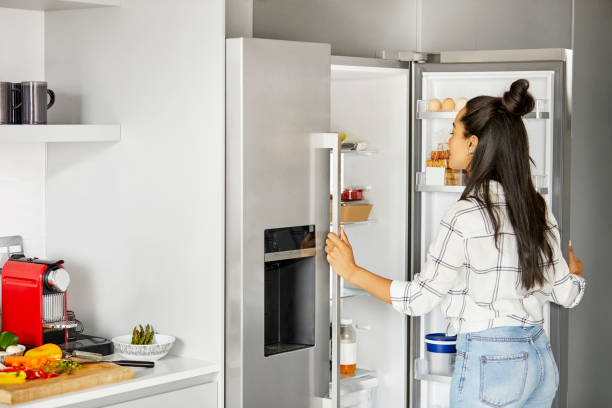 Woman looking for food in refrigerator at home stock photo