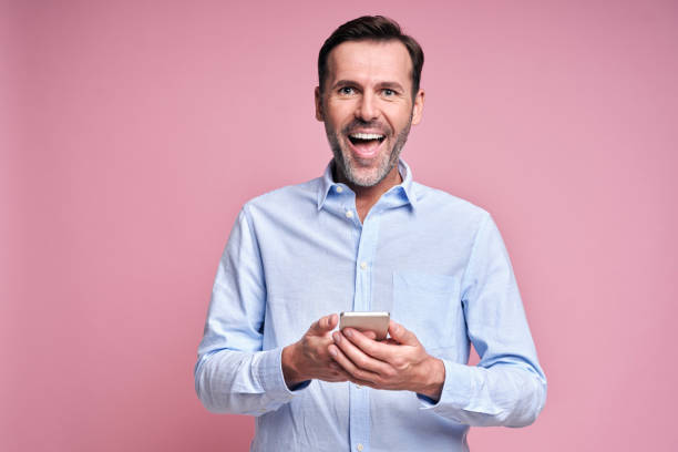 istock Smiling man holding mobile phone in hands 1350840399