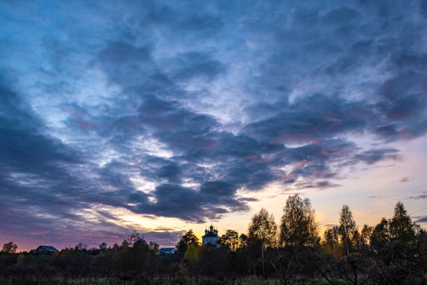 Beautiful evening cloudy sky with church domes and trees, Russia.